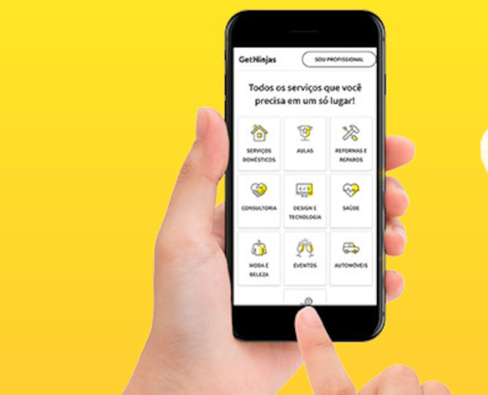 Uma mão segura um celular com o app da Getninjas aberto, mostrando as possibilidades para ganhar dinheiro.